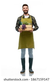 Gardening, Farming And People Concept - Happy Smiling Male Gardener Or Farmer In Apron And Rubber Boots With Box Of Garden Tools Over White Background