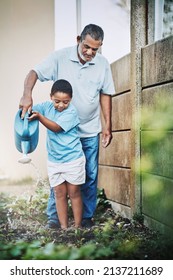 Gardening Helps Children Learn Life Lessons About Kindness And Care. Shot Of A Little Boy And His Grandfather Using Watering The Garden Together Outdoors.