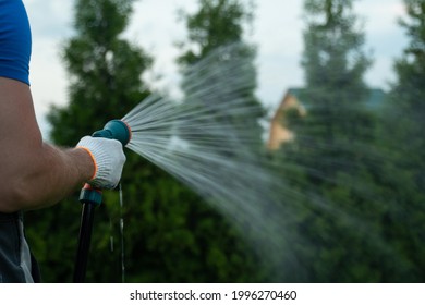 Gardening And Maintainance- Close Up Of Man Hands With Hose Watering The Lawn