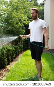 Gardening. Man Watering A Lawn With A Garden Rubber Hose.