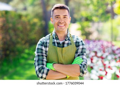 gardening and people concept - happy smiling middle-aged man in apron with crossed hands at summer garden - Powered by Shutterstock