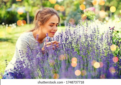 gardening and people concept - happy young woman smelling lavender flowers at summer garden over festive lights background - Powered by Shutterstock