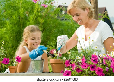 Gardening, Planting - Mother With Daughter Planting Flowers Into The Flowerpot