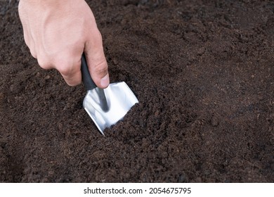 Gardening spade in compost soil. Close up of garden trowel in the ground on the garden bed digs a hole for planting seeds - Powered by Shutterstock