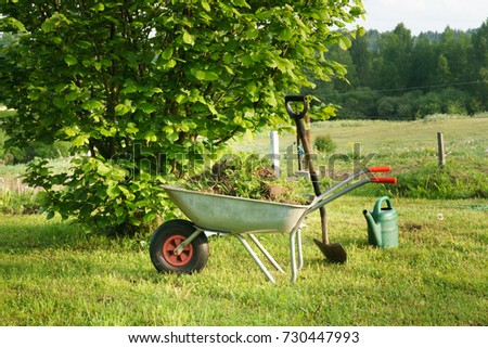 Gardening tools wheel barrow, shovel and watering can in morning