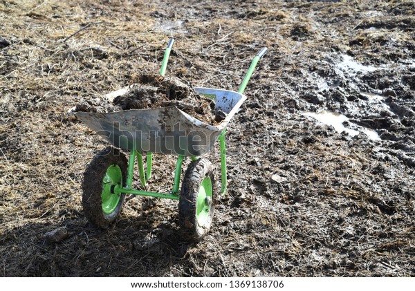 Garden-wheelbarrow filled\
with soil on a\
farm.