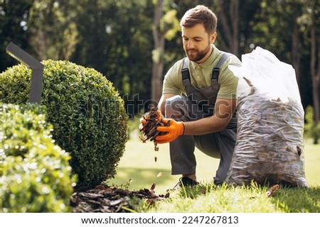Gardner holding package of tree bark to cover the ground