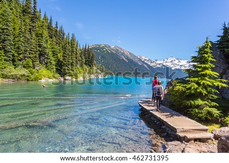 Garibaldi provincial park and lake with turquose water on a sunny day. Snow mountain at the background. Hikers on the trail.