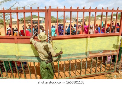 GARISSA, KENYA - AUGUST 14, 2019 - Ifo Security Guard Guarding At The Camp Entrance, The Somali People Waiting To Enter The Camp Gate For Get Limited Food Assistance In The Dadaab Refugee Camp . 