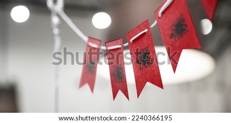 A garland of Albania national flags on an abstract blurred background