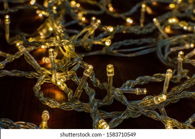 Garland For The Christmas Tree On A Background Of Dark Wood. Close Up, Back Drop, Bokeh.
