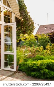 A Garland With Light Bulbs In The Country House's Garden. Landscape Design Of The Yard. Care Of Garden Plants.