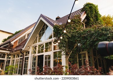 A Garland With Light Bulbs In The Country House's Garden. Landscape Design Of The Yard. Care Of Garden Plants.