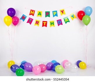 Garland that says happy birthday on a white background with multi-colored balloons