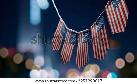 A garland of US national flags on an abstract blurred background.