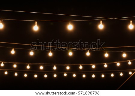 Garlands of lamps on a wooden stand on the street. A wedding Banquet.
