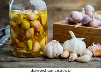 Garlic aromatic flavored oil or infusion bottle and wooden crate of garlic cloves on wooden kitchen table.  - Powered by Shutterstock