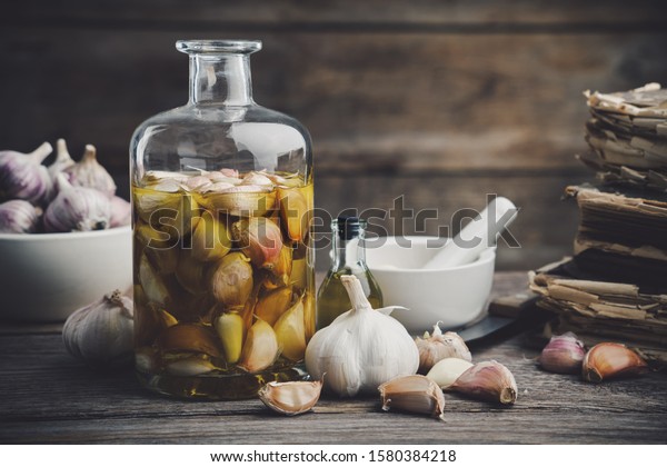 Garlic\
aromatic flavored oil or infusion bottle and garlic cloves. Mortar,\
old recipe books, kitchen knife. Garlic cooking.\
