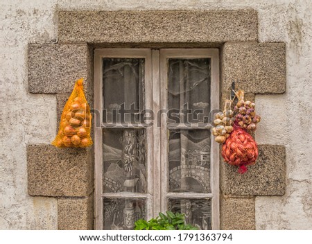 Garlic braid and onions hanging on old window for direct marketing