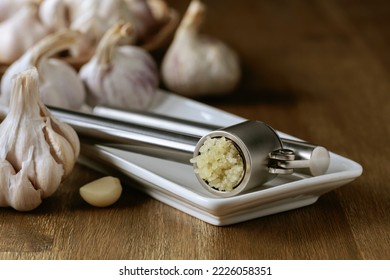 Garlic bulbs and garlic press on an old wooden table. 