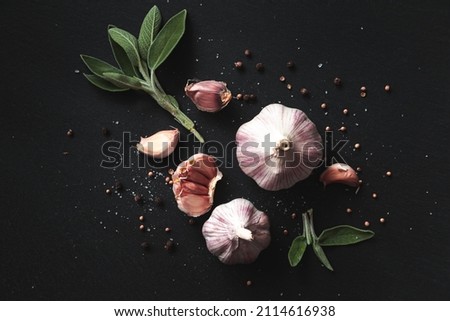 Garlic bulbs, spices, herbs and garlic cloves on a black background. Close-up, flat lay, top view. Food background, selective focus. 
