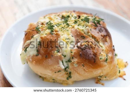 A garlic cheese bread roll herb garnish baked bun melted cheese parsley thyme golden crust breakfast