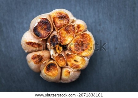 Garlic clove grilled on black stone background; top view.