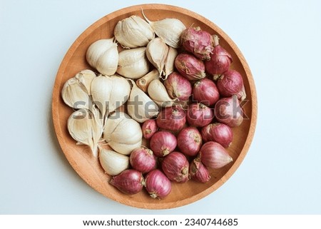 Garlic cloves and red onion or shallots on wooden plate, isolated on white background. Flat lay or top view