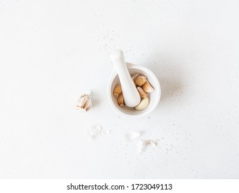 Garlic cloves in a white mortar with a pestle on a table in the kitchen. Top view. copy space

 - Powered by Shutterstock