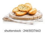 Garlic crisp bread Slices Topped With Herbs on cutting board isolated on a white background.