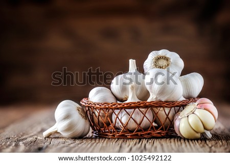Garlic. Fresh garlics in wooden basket. Pile of spice cloves.
