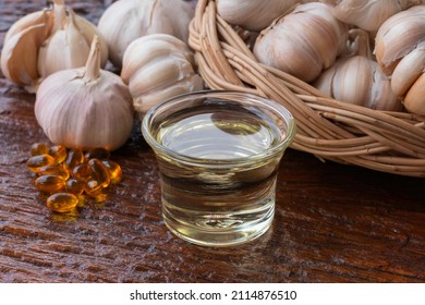 Garlic Oil And Garlic Bulbs On Brown Rough Wooden Background, Garlic Help Lower Cholesterol Levels, And Blood Lipid Levels.