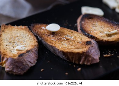 Garlic on toasted bread; preparing buschetta on a plate with toasted bread and garlic