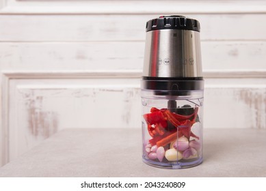 Garlic, shallots, pieces of red chili, and various other spices are placed in the small electric food chopper container, before being pureed.