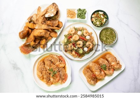 Garlic shrimp stir-fry, fried Ruby fish served with spicy sauce on white plate and stir fried stinky vegetables with shrimp and noodles asian cuisine gourmet dish.