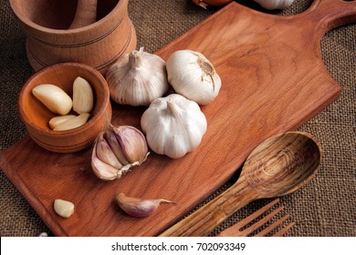 Garlic. sliced garlic, garlic clove, garlic bulb in wooden bowl place on chopping block on vintage wooden background. Place for text,  copy space Concept of healthy food. Top view - Shutterstock ID 702093349