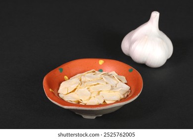 Garlic and sliced ​​garlic in a small bowl on black background - Powered by Shutterstock