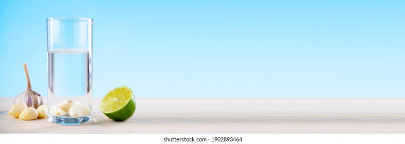 Garlic water with lime on a wooden table on a blue background, water with garlic, water with lemon, disease prevention. - Shutterstock ID 1902893464