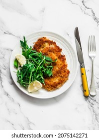 Garlicky bread crumbs crispy turkey chop and fresh lemon arugula salad on a light background, top view             - Shutterstock ID 2075142271