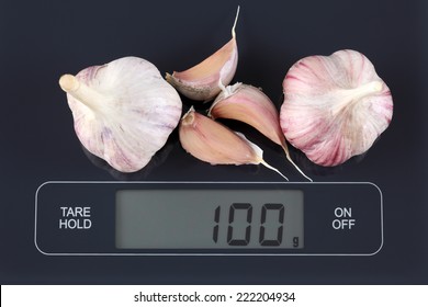 Garlics On Digital Scale Displaying 100 Gram.