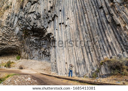 Garni basalt gorge in Armenia in Kotayk district, near the village of Garni. In the foreground, a tourist takes photos