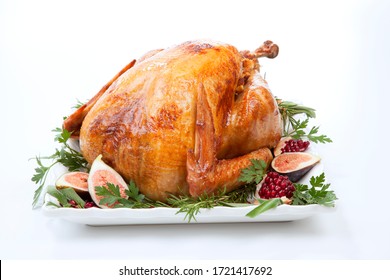 Garnished traditional roasted turkey, garnished with fresh figs, pomegranate, and herbs. On white background.