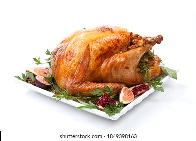Garnished traditional roasted turkey, garnished with fresh figs, pomegranate, and herbs. On white background.