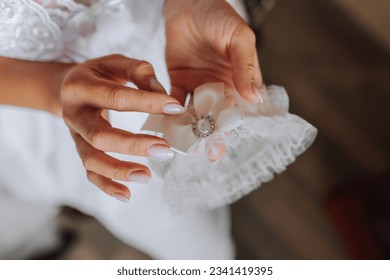 Garter on the leg of the bride in her hands, close-up. Morning of the bride - Powered by Shutterstock