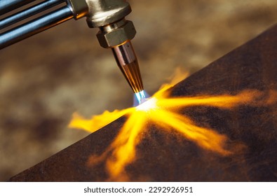 Gas cutting of metal. Gas cutter with copper nozzle with a stream of fire directed at the metal. Heating up the metal with a gas cutter. - Powered by Shutterstock