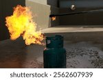 A gas cylinder emits a burst of flames, highlighting safety concerns related to gas leaks and fire hazards in industrial settings.