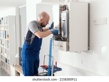 Gas Engineer Checking And Cleaning A Boiler During The Inspection At Home