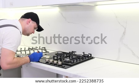 A gas engineer repairs a gas stove in the kitchen. The call of the master gas fitter to the house. 