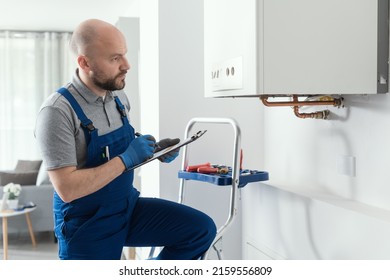 Gas Engineer Writing A Gas Safety Certificate And Boiler Records After Servicing