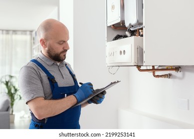 Gas Engineer Writing A Gas Safety Certificate And Boiler Records After Servicing